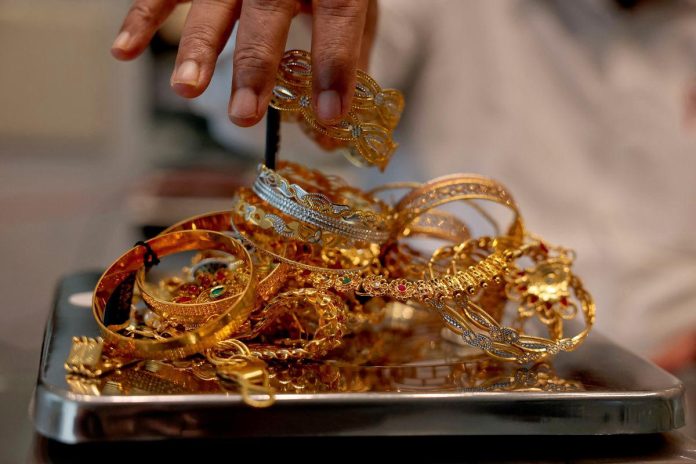 Gold edges up but heads for weekly loss on strong dollar