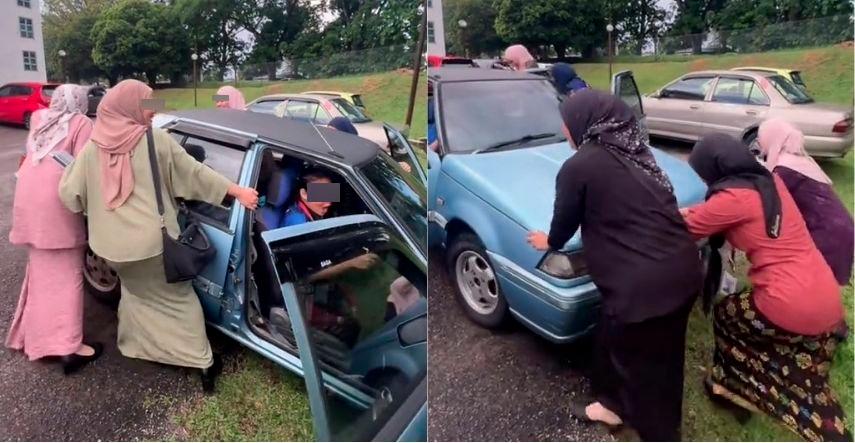 Malaysian women in traditional attire work together to move Proton Iswara out of drain 