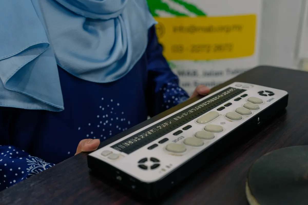 Izati uses the same braille display to edit books and prepare emceeing scripts.