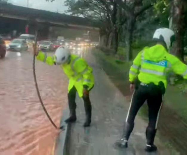 M’sian traffic officers in JB unclog drains near busy road in heavy rain, netizens impressed