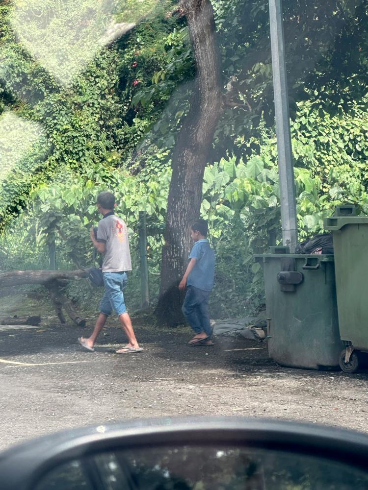 Kind woman gives RM20 to impoverished father and son looking for toys in rubbish bins