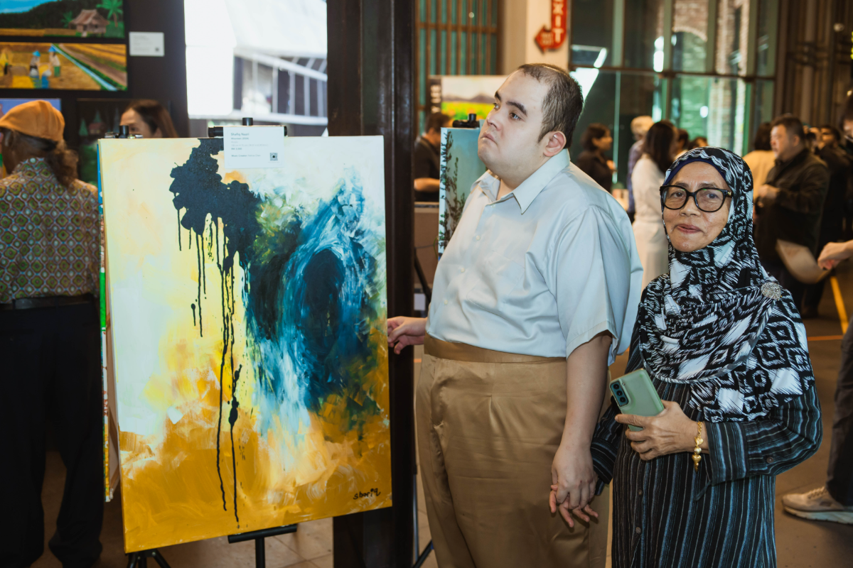 Shafiq (left) paints from memory, using bright colours, brushes and his fingers to build abstract works.