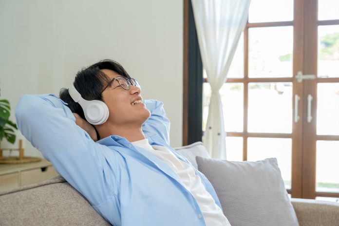 Relaxed man listening to music with headphones on the sofa at home A good pair of headphones can bring out details that small speakers often miss.